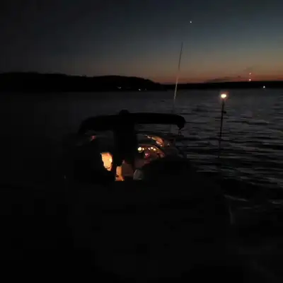 The boat running in at dusk, lit up against an orange horizon